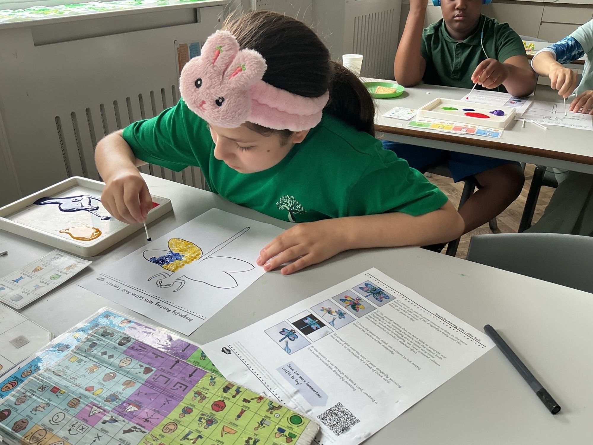 Pupil in classroom painting a butterfly picture