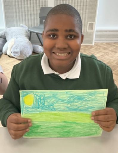 Pupil holding up landscape picture 