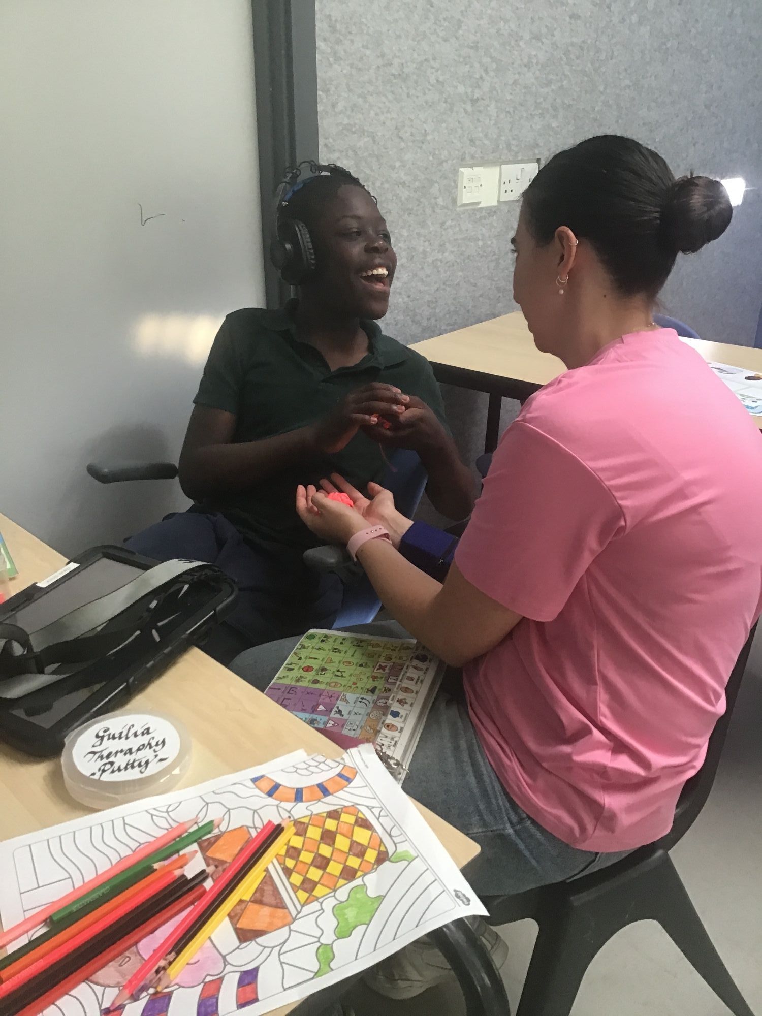 Pupil with headphones interacting with a staff member 