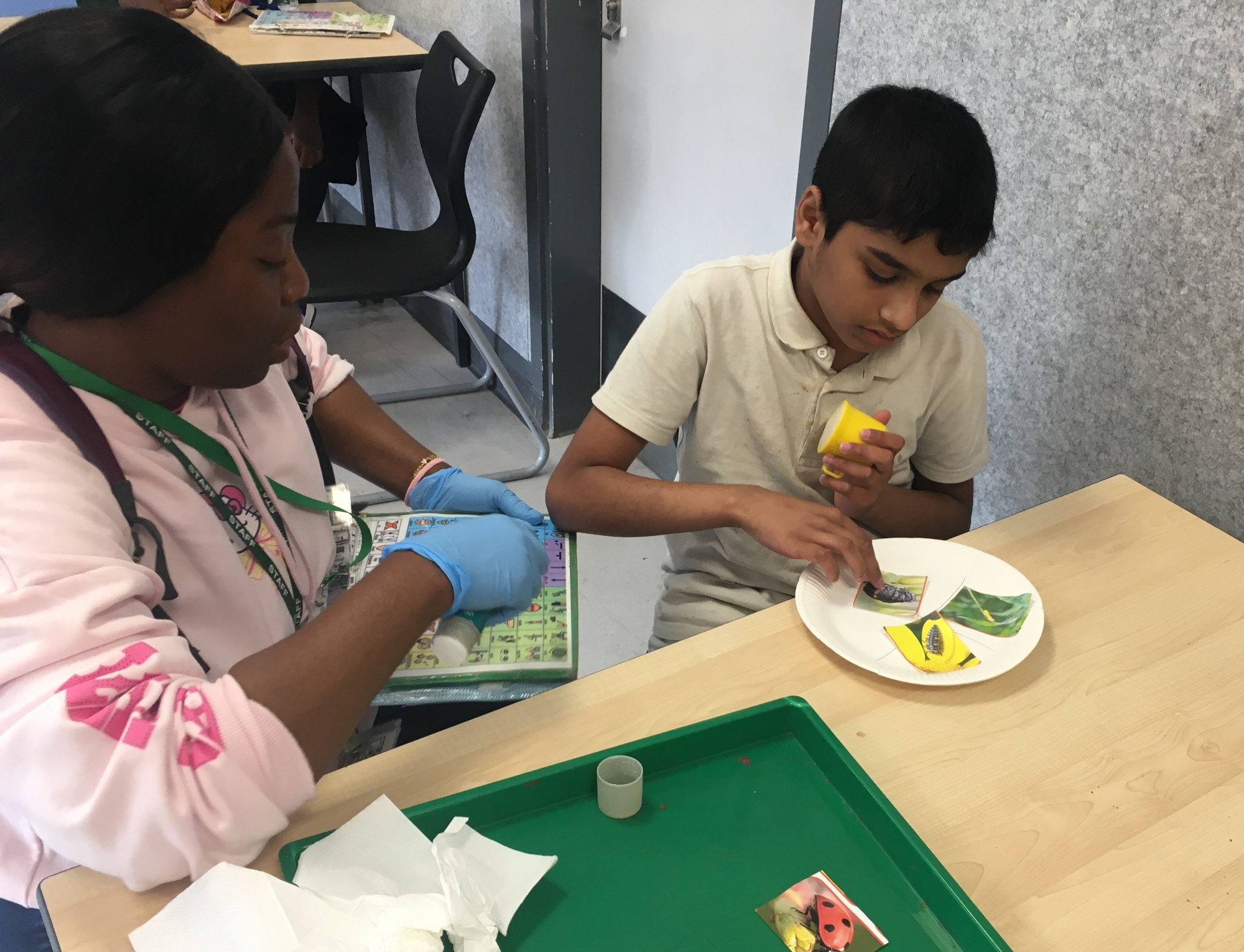 Pupil completing sticking activity with staff member
